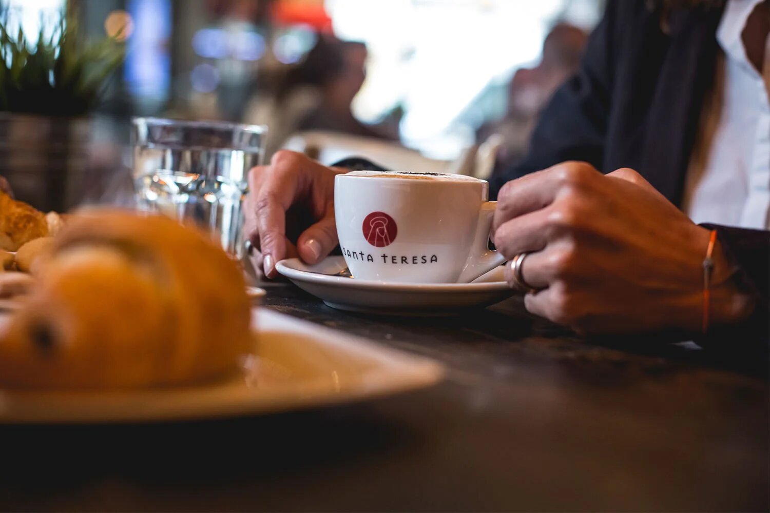 Una mujer tomando un café y un croissant en Santa Teresa Jorge Juan